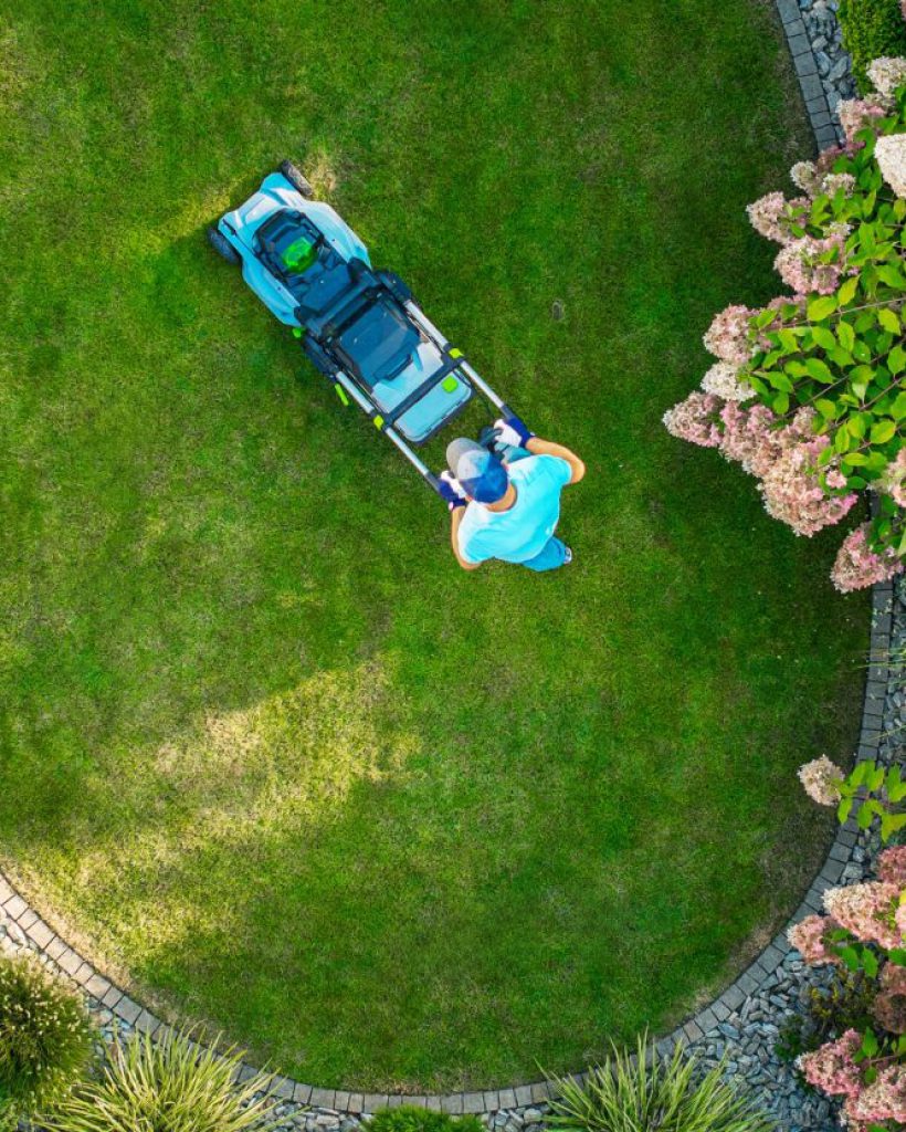 a-person-mowing-a-circular-lawn-surrounded-by-colorful-flowers-in-a-landscaped-garden.jpg